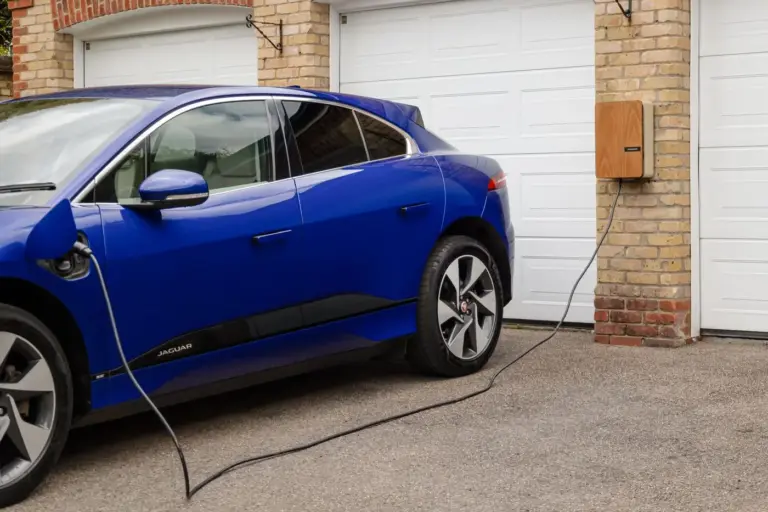 Blaues Elektroauto lädt zu Hause an einer Wallbox