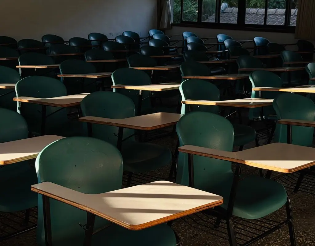 Leeres Klassenzimmer mit Tischen — die Materialien sind ohne Anmeldung im Unterricht nutzbar