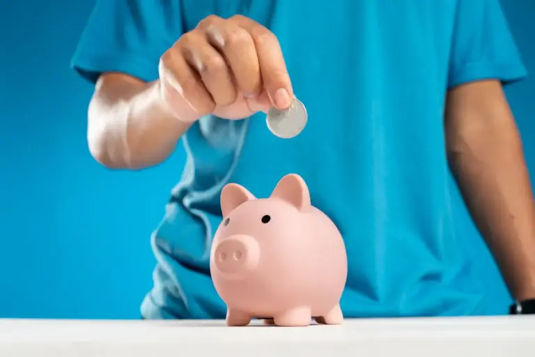 Kinderhand steckt eine Münze in ein Sparschwein
