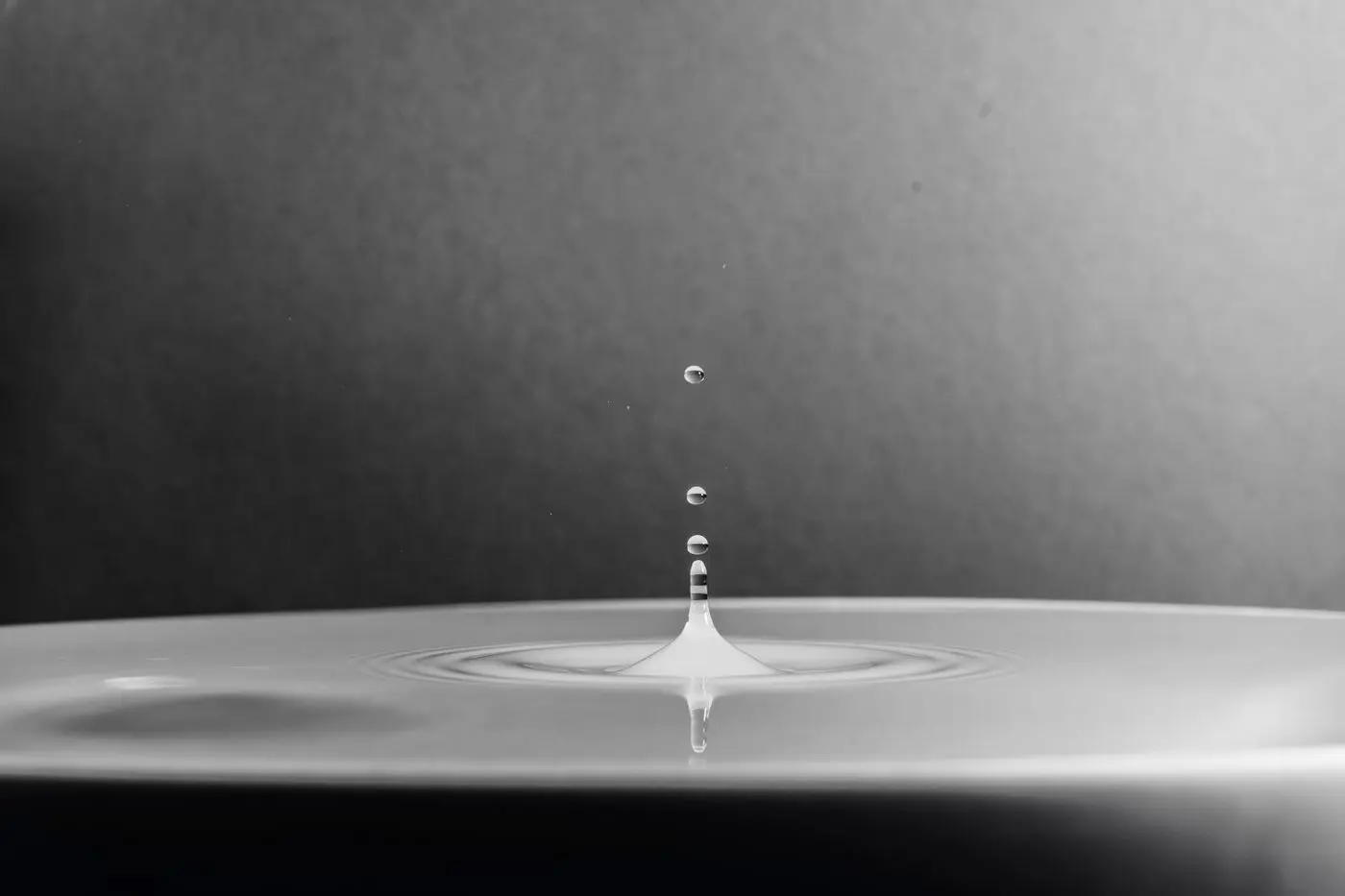 Makroaufnahme eines Wassertropfens auf einer Wasseroberfläche — regelmäßige kleine Beträge wirken über die Zeit