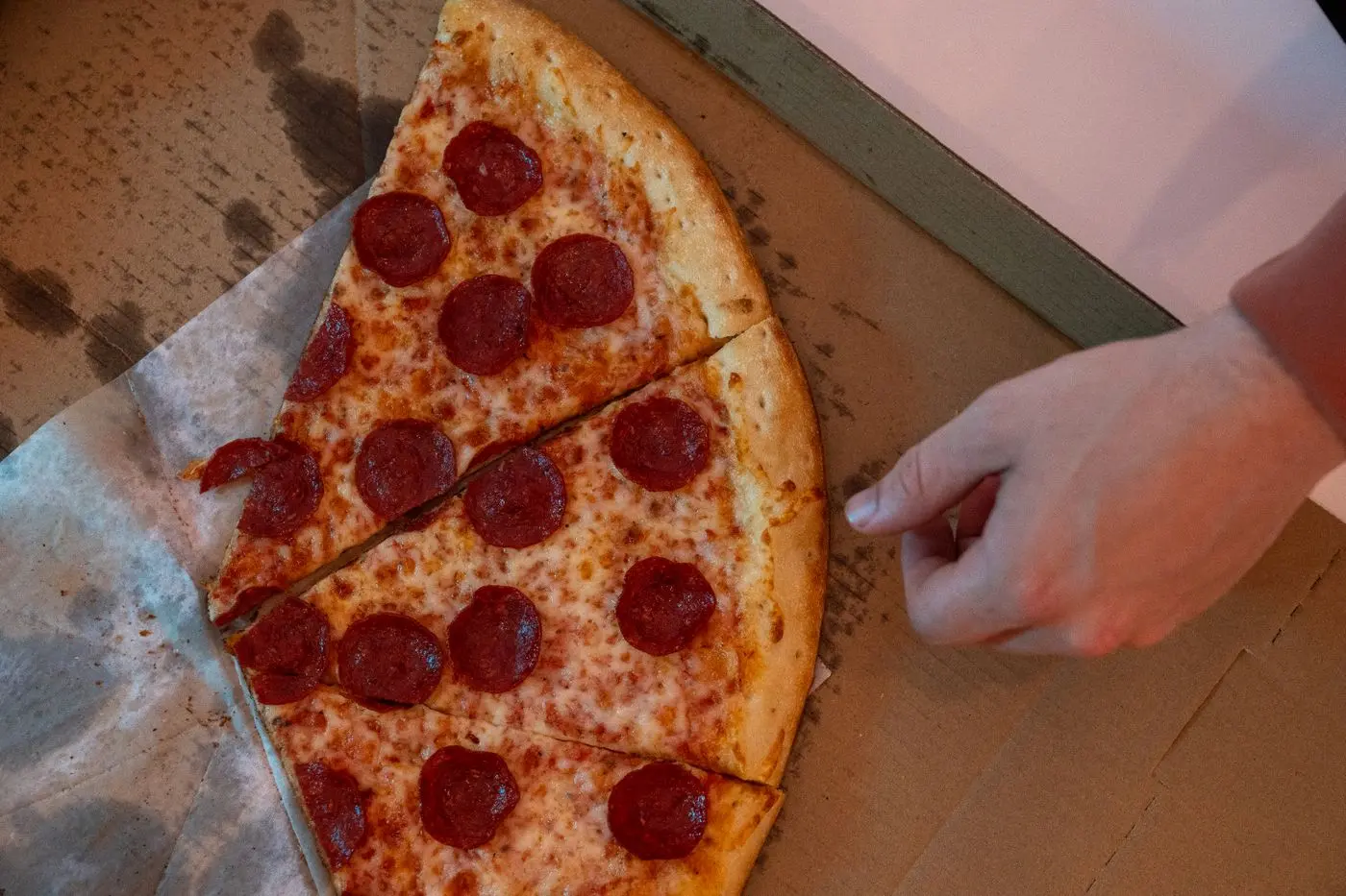 Hand greift nach einem Stück Pizza — für bedrucktes Papier bekommst du echtes Essen, weil alle mitspielen