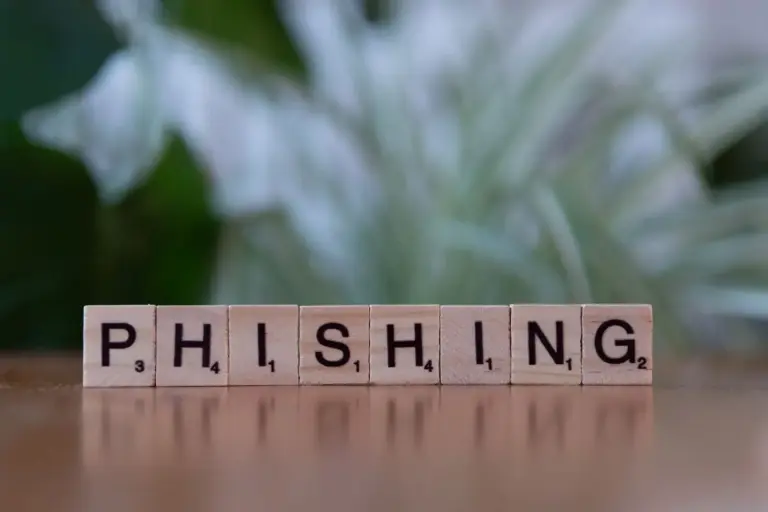 Holzwürfel mit Buchstaben bilden das Wort Phishing auf dunklem Untergrund